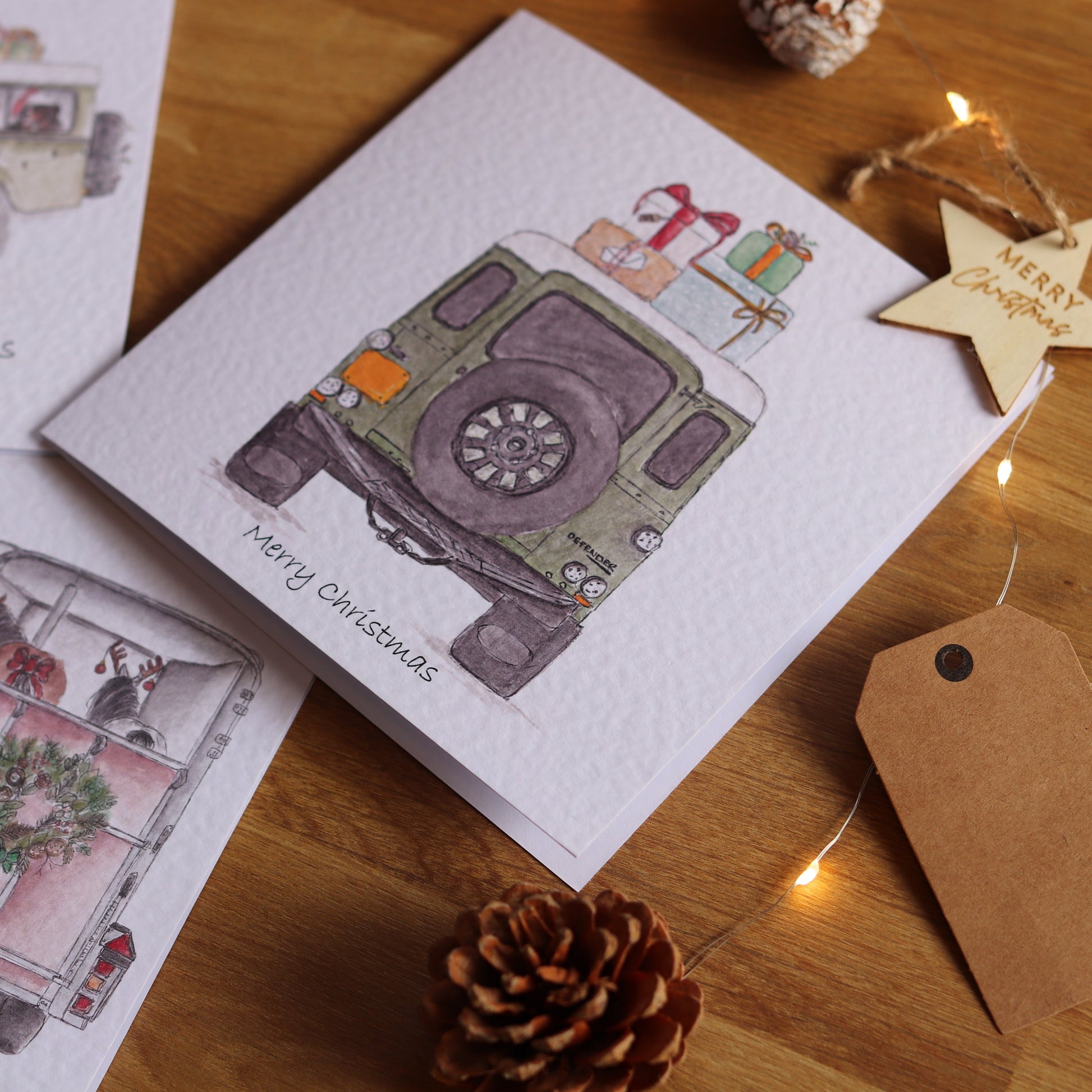 Christmas cards with festive illustrations of vehicles on a wooden surface.