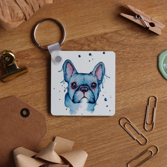 Keyring with a french bulldog illustration on a wooden surface.